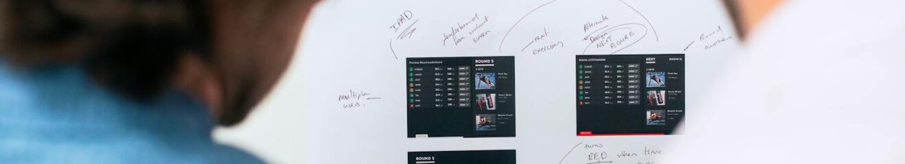 Two business professionals brainstorming and planning software development with a whiteboard in an office.